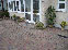 Thumbnail of the process of a block paved driveway with flower bed, brick wall surrounding property.
